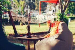 Espace chillout ombragé avec hamacs, poufs et narguilé autour d’une table